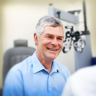 Older man smiling during an eye exam.