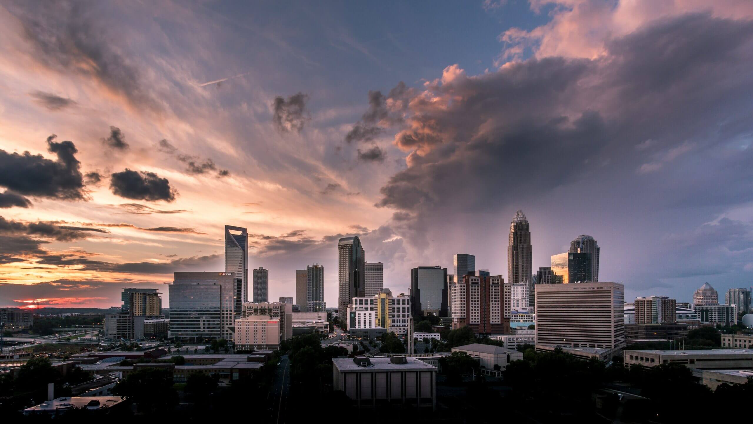 Sunset over a city skyline with dramatic clouds.